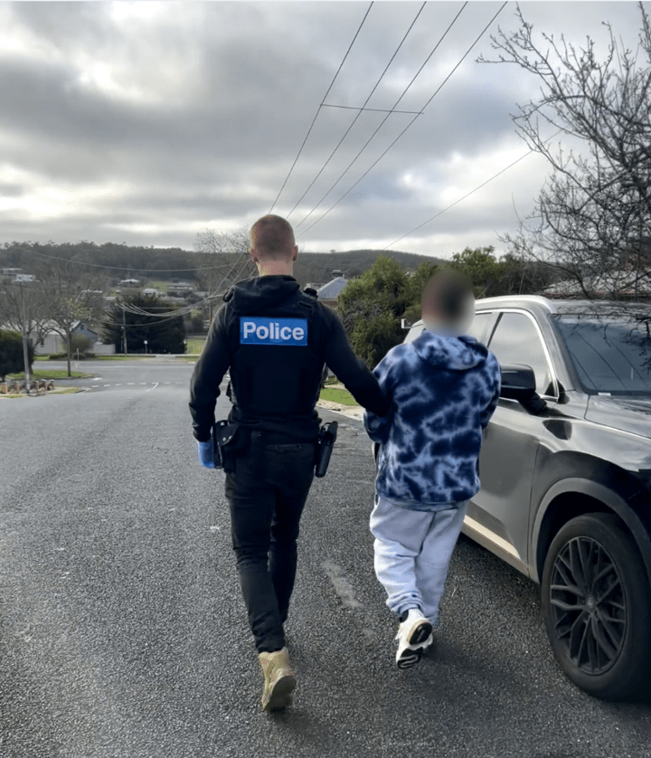 Police leading the arrested Creswick man to a vehicle following the Ballarat cheque deception investigation